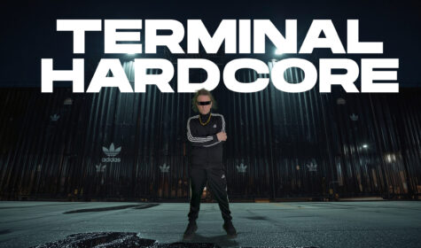 John B standing with arms folded, wearing a black and white adidas tracksuit